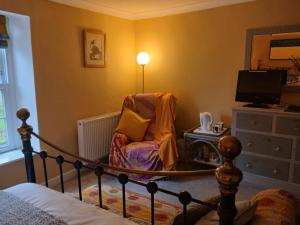 a bedroom with a bed and a chair and a television at Gospatric House in Ripon