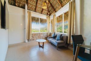 a living room with a couch and a table and windows at Villas & Resort Luz de Luna in Santa Cruz Huatulco