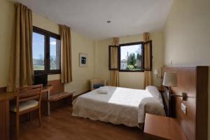 a bedroom with a bed and a desk and two windows at Hotel Ibaigune in Murueta