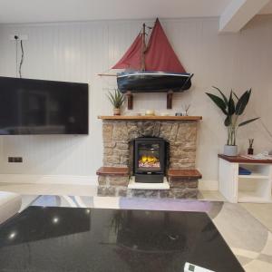 a living room with a fireplace with a boat on the wall at Roundstone Retreats Quayside luxury apt in Roundstone