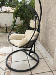 a wicker chair with pillows sitting on a patio at Studio climatisé SPA en option in Jacou