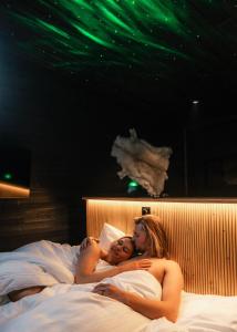 two naked women laying on a bed with green lights at Lapland Glow Chalets in Rovaniemi