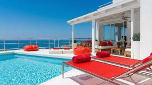 a villa with a swimming pool and red cushioned chairs at Villa Sitges Altavista Amazing View South oriented Calm Area AC Beach 2 minutes Drive and 18 minutes Walk in Sitges +38 photos