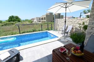 a swimming pool with a table and an umbrella at Villa Aster in Privlaka