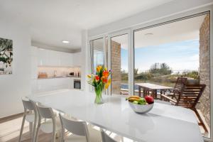 a white kitchen with a large white table with a bowl of fruit at Villa Aster in Privlaka