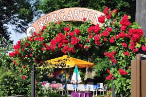 an entrance to a garden with red flowers and an umbrella at Westfalenkrug in Wuppertal