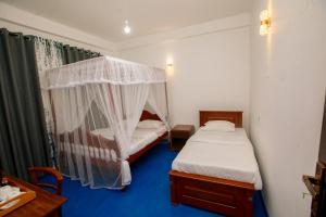 a bedroom with two beds and a mosquito net at Meadow Villa - Ella in Ella