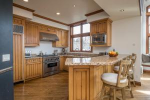a kitchen with wooden cabinets and a island with bar stools at Colonnade Residence 11 in Ketchum