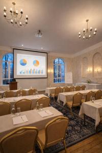 a conference room with tables and chairs and a screen at Viesnīca Meirānu Muiža in Meirāni