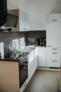 a kitchen with white cabinets and black appliances at FeWo Kibo Kupferberg in Kirchheimbolanden