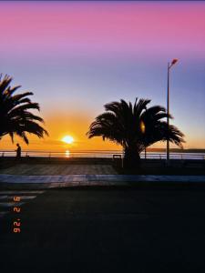 a sunset on the beach with two palm trees at MiraMar Casa Azul in Puerto Saavedra