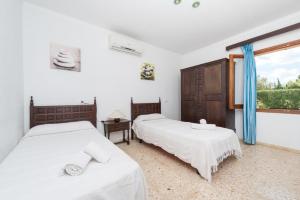 two beds in a white room with a window at Villa Canescandeu in Port de Pollensa