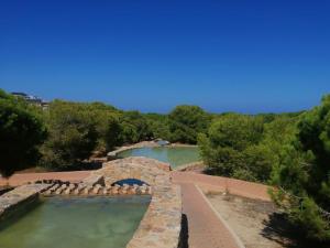 a swimming pool with a stone bridge in the water at Apartament La Mata -Maya Bungalow in Torrevieja