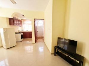 a living room with a television and a kitchen at Costambar Ocean Breeze - Beachfront Apartment with Pool in San Felipe de Puerto Plata