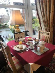 a table with a red table cloth with food on it at Glendale Guest House in Penrith