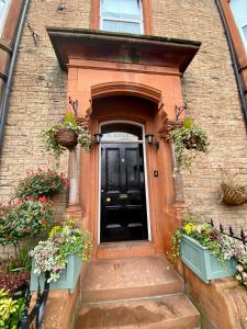 a black door on a brick house with flowers at Glendale Guest House in Penrith