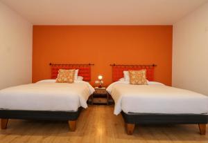two beds in a room with orange walls at Muru Suites near Plaza de Armas Cusco by Wynwood House in Cusco