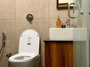 a bathroom with a white toilet and a sink at Sree Devi Grande in Chennai +25 photos