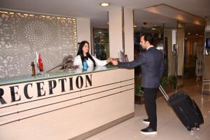a man and woman shaking hands at a reception counter at Asrin Business Hotel Kızılay in Ankara