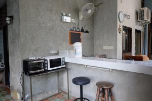 a kitchen with a counter with a microwave and a stool at Baan Ma Feung GuestHouse in Kanchanaburi City