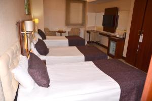 a hotel room with three beds and a television at Asrin Business Hotel Kızılay in Ankara