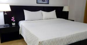 a large bed in a hotel room with two lamps at Gran Hotel CCP Suites in Maturín