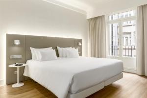 a large white bed in a room with a window at NH Collection Brussels Centre in Brussels