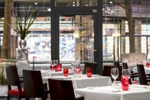 a restaurant with white tables and chairs with wine glasses at NH Collection Brussels Centre in Brussels