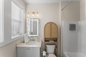 a bathroom with a sink and a toilet and a mirror at Riverview Retreat: Neyland Stadium – sleeps 8! in Knoxville +11 photos
