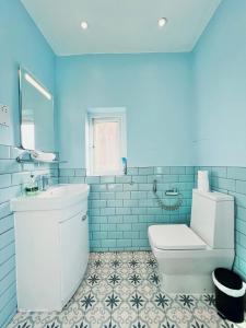 a blue bathroom with a toilet and a sink at Gants Hill House in Redbridge +32 photos