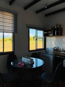 a kitchen with a table and some chairs and windows at El Descanso Cabins in Capilla Palacio +6 photos