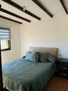 a bedroom with a bed with blue sheets and a window at El Descanso Cabins in Capilla Palacio