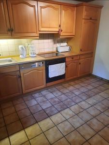 a kitchen with wooden cabinets and a tile floor at Oakwoods in Holste