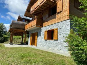 a house with wooden doors on the side of it at Chalet Robin (6 personnes) in La Lechere