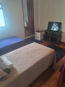 a bedroom with two beds and a flat screen tv at Sollarium Pousada in Diamantina