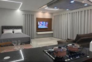 a living room with a bed and a kitchen with pots on a stove at Flat Cerejeiras - Condomínio Privado in Bananeiras