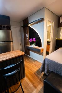 a bedroom with a bed and a kitchen with a window at Flat exclusivo Studi Cuiabá 1605 in Cuiabá +3 photos