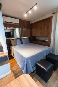 a small bedroom with a bed and a stool at Flat exclusivo Studi Cuiabá 1605 in Cuiabá