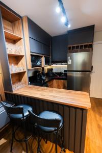 a kitchen with black cabinets and a refrigerator at Flat exclusivo Studi Cuiabá 1605 in Cuiabá