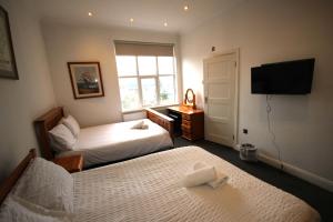 a hotel room with two beds and a flat screen tv at Isleworth Apt C in Hounslow