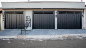 a building with three garage doors with a bench in front at Jahu Center Casas Un 2 in Jaú