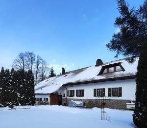 a white house with snow on the roof at Pension Pumperle in Strážný