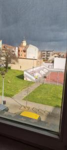 a window with a view of a field and a building at Apartman VASKE in Šabac