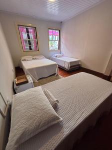 a room with two beds and two windows at Sollarium Pousada in Diamantina