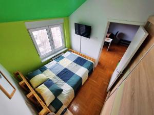 a bedroom with a bed and a green wall at XO Apartman in Sremska Mitrovica