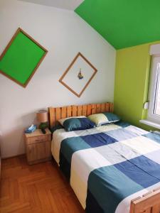 a bedroom with a large bed and a green wall at XO Apartman in Sremska Mitrovica