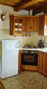 a kitchen with a white refrigerator and wooden cabinets at Budafai Vendégház in Kiscsehi +56 photos