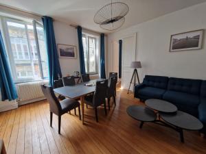 a living room with a table and a blue couch at Gîte Comme Chez Vous à Lunéville confort, calme et séjour en Lorraine in Lunéville