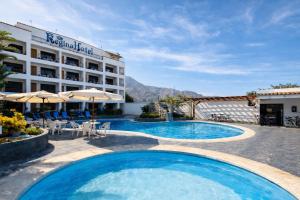 a hotel with two pools and tables and umbrellas at Regina Hotel in Lunahuaná