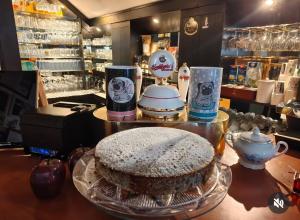 a cake on a glass plate on a counter with cups at Pension Pumperle in Strážný